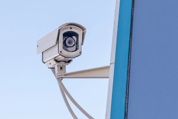 Überwachungskamera in einem Eingangsbereich, dazu Papiere mit Hinweisen zu Datenschutz und Rechtssicherheit.